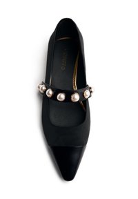 Black pointed-toe flat shoe with a strap across the top adorned with large white pearls on a white background.