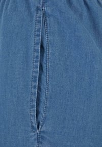 Kék farmeranyag közeli kép, függőleges hasított zseb dupla varrással.