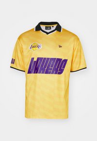 Gelbes Basketballtrikot mit schwarzem Kragen, das großen lila "LAKERS"-Text und Logo zeigt, aus glattem Stoff mit subtiler Muster-Hintergrund.