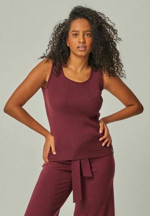 Burgundy ribbed tank top with a scoop neckline, paired with matching wide-leg pants featuring a tied waistband. Soft texture.