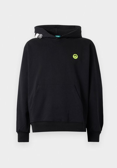 Felpa nera con tasca frontale, faccina sorridente verde neon con zanne sul petto e dettaglio logo bianco sul lato sinistro del cappuccio.