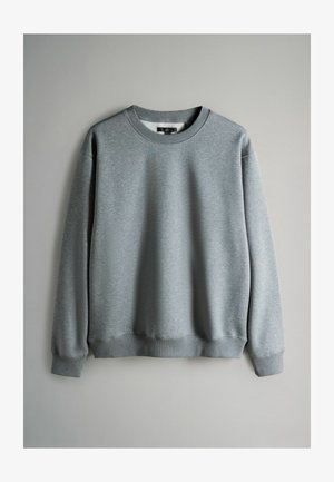 Sweatshirt gris en tissu doux, présentant un col arrondi et des poignets côtelés. Design simple et minimal sans motifs ni accents visibles.
