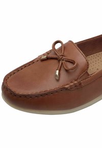 Mocassin en cuir marron avec détail nœud sur le devant, coutures visibles et semelle intérieure matelassée perforée.