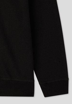 Czarny materiał dresowy o gładkiej fakturze. Posiada ryflowane mankiety i dół, z prostym, minimalistycznym wzornictwem. Brak widocznych wzorów lub akcentów.