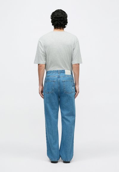 Hall halli lühikeste varrukatega t-särk ja hele sinised laiade säärega teksad, millel on tagumisel vöökohal patch-sildike ja kaks tagataskut.