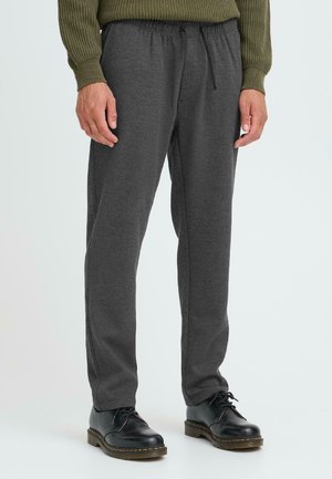 Pantaloni grigi con vita elasticizzata, di vestibilità affusolata, realizzati in tessuto morbido, con tasche laterali e cordino. Abbinati a scarpe nere con lacci.