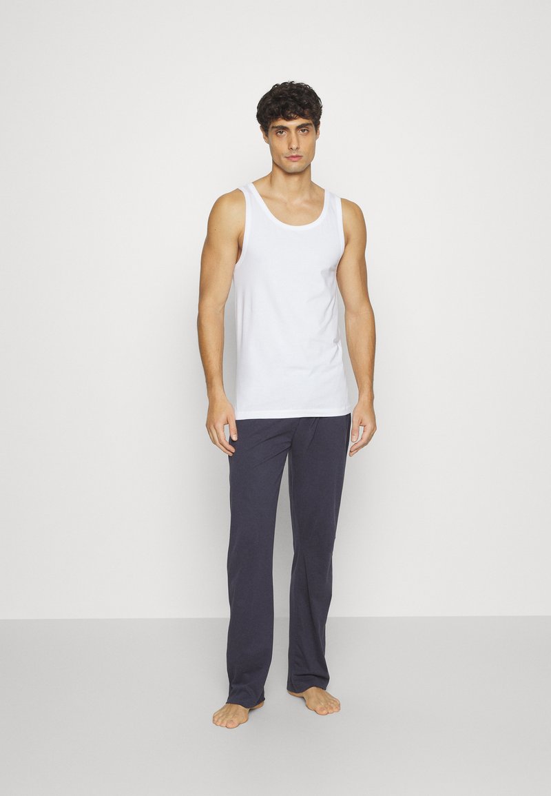 Top sin mangas de algodón blanco combinado con pantalones de pijama sueltos de color azul marino. El top tiene un escote redondo y tirantes anchos.