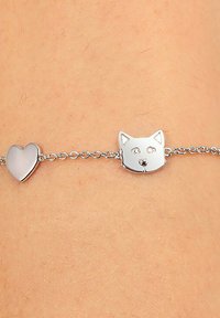 Bracciale in argento con ciondolo a forma di testa di gatto e ciondolo a forma di cuore, entrambi con texture lisce e finitura riflettente.