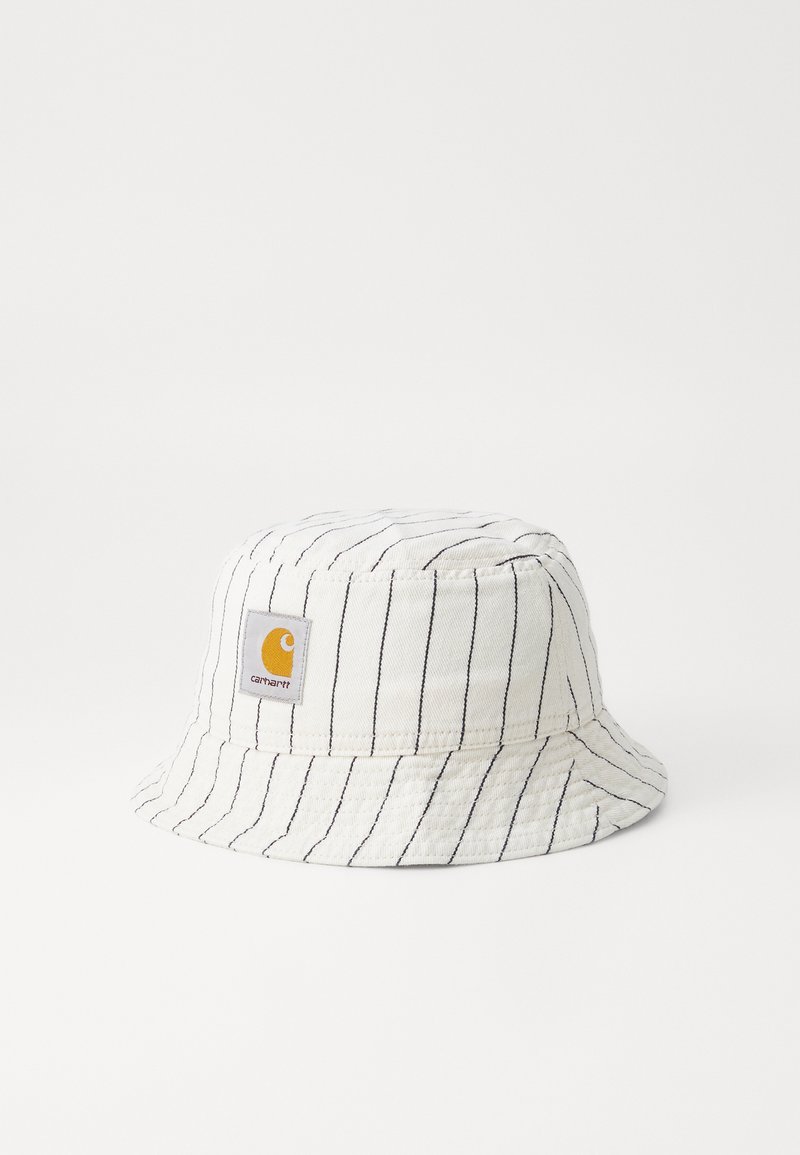 Chapeau seau blanc avec des rayures verticales noires, en coton. Présente un logo carré jaune sur le devant. Texture douce.