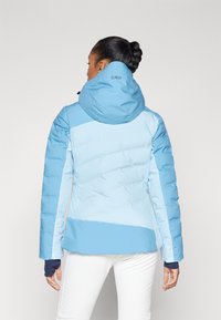 Women's blue puffy jacket featuring a color-block design, with a fitted shape, elastic cuffs, and adjustable hood for warmth and comfort.