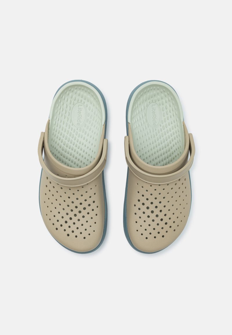 Beige Clogs mit einer strukturierten Oberfläche und mehreren Perforationen. Flexible Riemen und eine hellblaue Sohle, die eine gepolsterte Innensohle bietet.