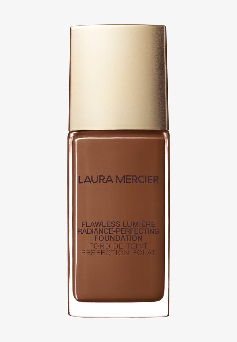 Brun glasflaske med et guldhætte. Etiketten viser "Laura Mercier Flawless Lumière Radiance-Perfecting Foundation" i mørk skrift.