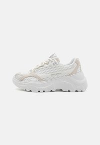 White mesh sneakers with silver and beige accents. Thick, textured outsole with a hexagonal pattern. Laces and padded collar for support.