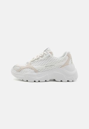 Białe siateczkowe sneakersy z srebrnymi i beżowymi akcentami. Gruba, teksturowana podeszwa z heksagonalnym wzorem. Sznurówki i wyściełany kołnierz dla wsparcia.