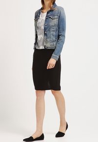 Lys blå denimjakke med to brystlommer, parret med en hvid skjorte med et sort blomstermønster og en sort ribbet blyantskørt.