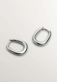 Pendientes de aro de plata con un acabado suave y pulido; forma ovalada con un ligero diseño retorcido, que cuenta con un cierre articulado para su sujeción.