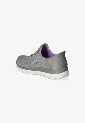 Zapatilla deportiva gris con una parte superior de tela texturizada, interior lavanda, un tacón bajo y una suela blanca flexible. Presenta un logo en el lateral.