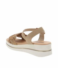 Sandali beige con cinturini incrociati, parte superiore testurizzata e suola imbottita. La piattaforma bianca presenta un sottile accento metallico vicino alla suola.