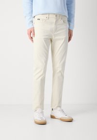 Lichtgekleurde katoenen chinos met een recht gesneden pasvorm, voorzien van vijf zakken en een subtiele merketiket. Gemaakt in combinatie met witte sneakers.