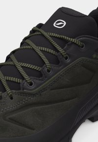 Μαύρο και σκούρο πράσινο πεζοπορικό παπούτσι με πράσινα κορδόνια με σχέδιο, μαξιλαρωμένη γλώσσα και ανθεκτική υφή στη σόλα.