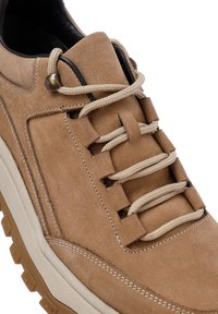 Zapatillas de ante en tono marrón claro con cordones beige, un cuello acolchado y una suela de goma texturizada con patrones de banda de rodadura angulares.