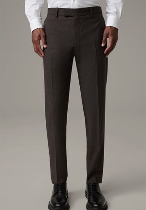 Slim-fit, dark brown trousers made of textured fabric. Featuring a flat front, crease lines, and belt loops. Paired with black leather shoes.