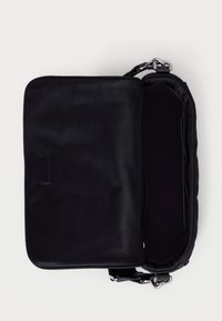 Črna sintetična torbica čez ramo z ravno obliko, gladko površino, zadrgo, notranjim žepom in prilagodljivim trakom. Ni vidnih zunanjih okovij ali vzorcev.