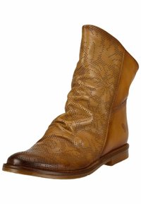 Bottines en cuir marron avec un design fléchi, motif floral perforé, bout pointu et petit talon en bois. Texture lisse et forme classique.