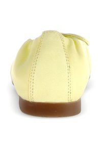 Geel lederen ballerina met een zachte, gerimpelde ontwerp bij de hiel en een bruine rubberen zool. Beschikt over zichtbare stiksels.