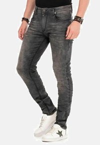 Grijze denim jeans met een slank ontwerp, voorzien van subtiele vervaging, gestikte accenten langs de zijkanten en een vijf-pocket stijl. Witte sneakers maken de look compleet.