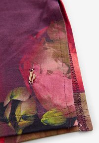 Korte mouwen shirt in een paars en bloemrijk patroon, met gedetailleerde stiksels en een klein gouden accent met het "b" logo nabij de zoom.