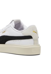 Baskets blanches avec des accents en daim noir, bout rond et col rembourré. Présente un logo doré et une semelle en caoutchouc texturée.