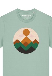 Mintgroene T-shirt met een cirkelvormige afbeelding van een zon en gelaagde bergen in bruin, groen en zwarte tinten, gemaakt van zachte katoen.