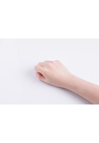 En ljus hy, slät hand vilar på en vit yta, med fingrarna lätt krökta och naglarna klippta, vilket ger ett naturligt utseende.