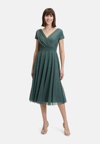 Sukienka w kolorze zieleni morska o długości do kolan, z krótkimi rękawami, dekoltem w kształcie litery V i marszczoną talią, z efektem połysku i lejącym się dołem.
