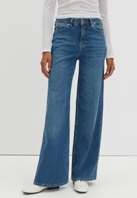 Jean bleu à jambes larges en denim, doté de cinq poches, d'une fermeture éclair et d'une coupe décontractée. Le tissu présente une légère texture et un effet délavé.