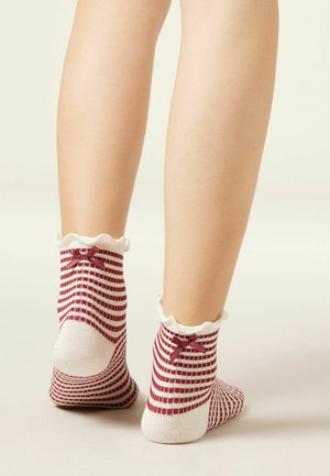Legs wearing white ankle socks with red checkered pattern, scalloped edges, and small red bows on the back.