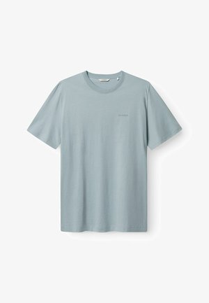 Gaiši zils īsroku T-krekls no mīksta auduma ar apaļu kakla izgriezumu un smalki izceltiem logotipa elementiem kreisajā pusē.