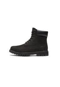 Bottines en daim noir avec un col rembourré, bout rond, devant à lacets à six œillets et semelle en caoutchouc robuste. Présente un logo embossé sur le côté.
