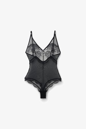 Černý korzetový overal z krajky s květinovým vzorem, hlubokým výstřihem, nastavitelnými ramínky a vroubkovanými okraji. Měkký síťovaný materiál se zapínáním na knoflíky.