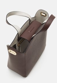 Borsa in pelle marrone con un design strutturato, dotata di manici color crema, accessori in oro e dettagli perforati sulla parte anteriore.