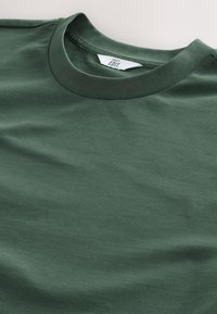 Dunkelgrünes T-Shirt mit Rundhalsausschnitt aus glattem Baumwollstoff, mit einfachem Design ohne sichtbare Muster oder Verzierungen.