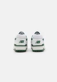 Sneakers bianchi con accenti verdi, materiali in pelle e rete, lacci piatti e suola in gomma texturizzata. Logo visibile sul tallone.