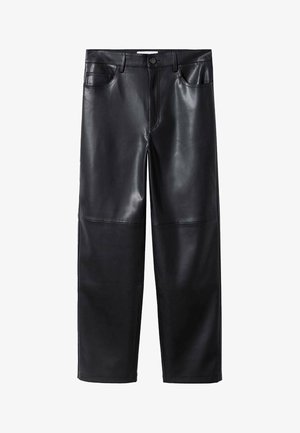 Kobieta w czarnych skórzanych spodniach o długości 7/8, białym i czarnym swetrze w paski na niebieskiej koszuli, czarnych skarpetkach i czarnych mokasynach z złotym łańcuszkiem.