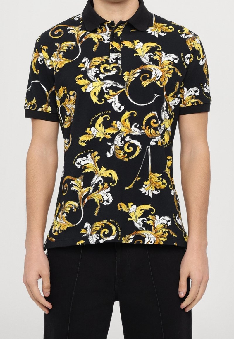 Polo noir avec un motif floral jaune et blanc complexe, manches courtes et col noir contrastant.