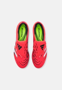 Scarpe da ginnastica rosse con upper testurizzato, dotate di accenti neri e bianchi, e una soletta verde brillante con la scritta "PREDATOR".
