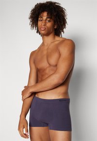 Marineblaue SLOGGI Boxershorts mit nahtlosem Design, elastischem Bund und strukturiertem Stoff, vor einem neutralen Hintergrund präsentiert.