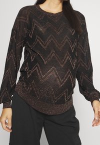 Maglione nero con maniche lunghe, motivo a zigzag in oro rosa metallico, polsini e orlo a coste. Tessuto a maglia leggero e leggermente trasparente.