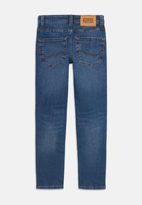 Blue denim jeans with a straight fit, featuring a leather back patch, two rear pockets, and contrasting stitching.