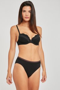 Sostenedor negro de encaje con aros y bordes festoneados, adornado con un pequeño lazo en el centro; conjunto de braguitas negras a juego con una cintura a rayas roja y blanca.